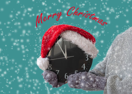 Hands in mittens to hold the watch, which is wearing a Santa Claus hat around the snow postcard...