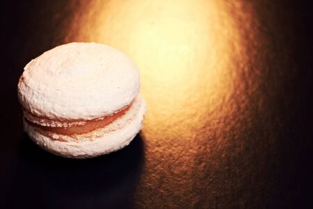 Tasty pink baked macaroon in the lights warm lamp. Delicious food. Food and drink background with...