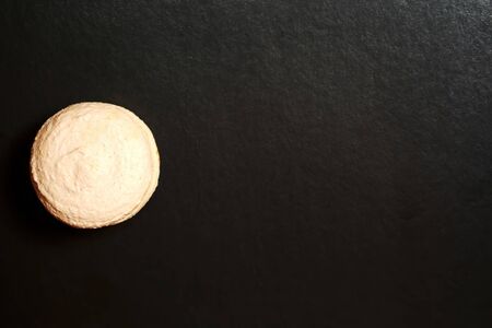 Flat lay template with a tasty macaroon on the black table surface. Food and drink backgrounds. Copy...