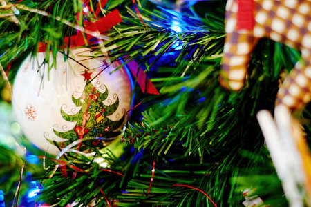 Decorative festive ball hanging on a green Christmas tree. Holiday interiors and backdrops