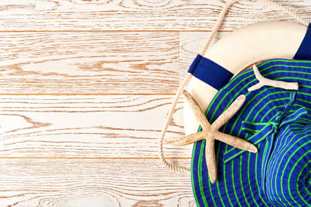 Blue womens hat, ocean lifebuoy and corals on the wooden surface. Flat lay design mockup for travel...