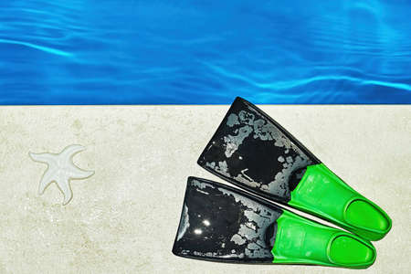 Colorful childrens flippers and starfish on the tiles at the edge of the pool. Snorkeling and...