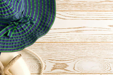 Green wide hat, lifebuoy, corals and starfish on the wooden background surface. Flat lay design template for travel backdrops with copy spaceの写真素材
