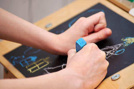 Little boy drawing Christmas scene on the chalkboard. Childhood, inspiration and creativity