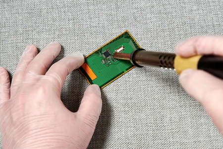 A worker in gloves repairing a pcb with a microchip. New technologies and manufacturingの写真素材