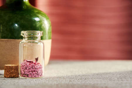 Transparent jar with pink scented petals in the spa salon. Makeup and healthcare backgroundsの写真素材