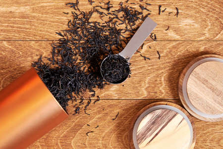 Black tea brew scattered from a metallic jar on the wooden table with a spoon. Tea ceremony...
