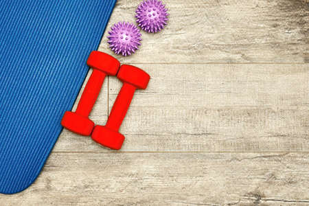 Fitness mat, massage ball, dumbbell and sports equipment on the wooden floor. Workout concept and accessoriesの写真素材