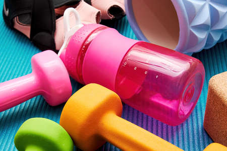 Fitness equip, sneakers, dumbbell, roller, bottle, bricks lay on the mat. Sports equipment and workout backgroundsの写真素材