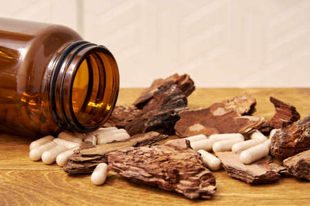 Herbal pills with powder scattered from the brown glass jar on the table. Herbal medicine and homeopathyの写真素材