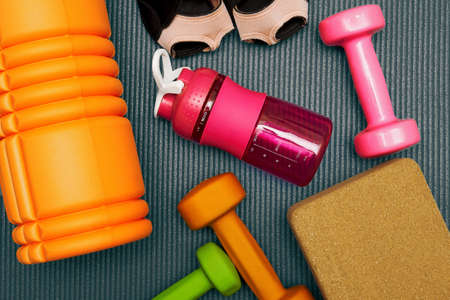Toned flat lay template with fitness equipment, dumbbell, roller, bottle on the mat. Gym eqip and healthcare backgroundsの写真素材