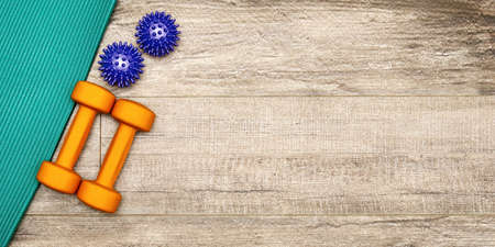 Banner template with fitness equipment on the wooden floor with copy space. Sports mat, dumbbells and balls for active exercisingの写真素材