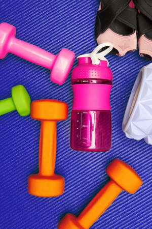 Vertical still life with fitness equipment, dumbbell, roller, bottle on the mat. Gym eqip and healthcare backgroundsの写真素材