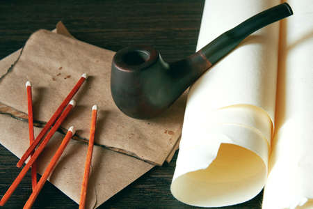Vintage image of classic smoking pipe on the letters and papers. Wooden mans cabinet