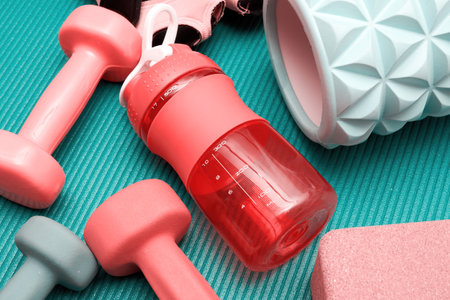 Fitness backdrop with sports stuff on the mat in the gym. Mat, dumbbell, massaging ball, bottle. Healthy lifestyle and sport actionsの写真素材
