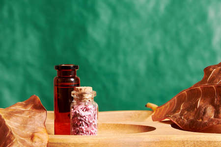 Hair tonic liquid and jar with scented petals on the tray in the cosmetic shop. Beauty and fashion...