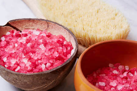 Bowl and coconut with the pink bath salt grain and wooden brush. Spa procedure and treatment...
