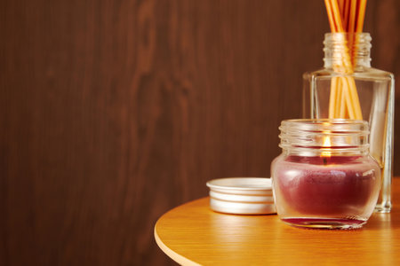Scented aroma candles, perfume and sticks on the wooden table. Cozy interior and atmosphere for...