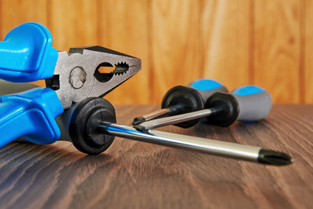 Worker equip, screwdriver and pliers on the wooden table in workshop. Instruments and tools...
