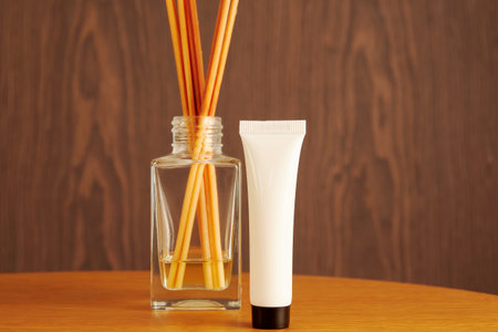 Plastic white beauty cosmetic bottle with aroma cream on the wooden table. White template with place...