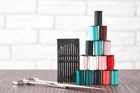 Pastel colored tailor threads stacked in pyramid form with scissors and needles. Embroidery theme...