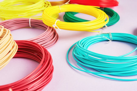 Many colorful PLA and ABS plastic skeins on the table. 3D pen equipment. Hobby and craft backgroundsの写真素材