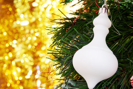 Christmas template with golden lights and evergreen tree branch with white toy bauble. Happy holidays and event backgrounds. Copy space for textの写真素材