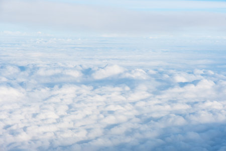 Wide carpet of soft white cumulus clouds high in the sky. View from airplane