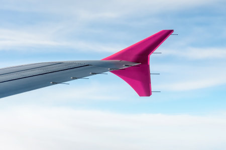 Detailed airplane wing with pink fin high up in the sky. View from airplane, travel and transportationの写真素材