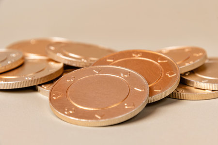 Stack of gold casino chips with a subtle texture on a light brown surface. Gambling and betting concept and symbolの写真素材