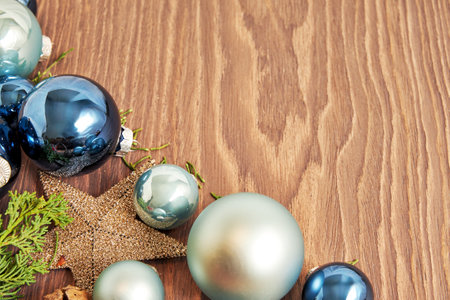 Close-up of blue and green Christmas ornaments arranged on a wooden background. The ornaments are shiny and reflect the light with festive atmosphereの写真素材