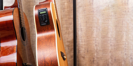 Two acoustic guitars stand side by side, one with a built-in equalizer. Wide banner with copy space...