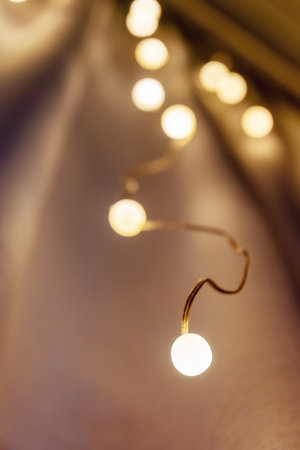 Garland with warm, golden lights creates a beautiful bokeh effect against a soft, blurred...