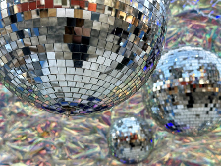 Close-up shot of a disco ball reflecting light and colors. The image features multiple disco balls of varying sizes, creating a dazzling compositionの写真素材