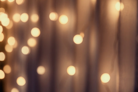 Garlands with warm, cozy lights creates a beautiful bokeh effect against a soft, blurred background. Cozy festive decorationの写真素材