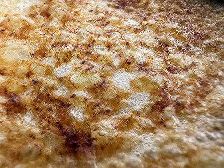 Delightful, golden-brown texture of a freshly cooked dessert. The surface showcases a delicious combination of crispy edges and tiny air bubblesの写真素材