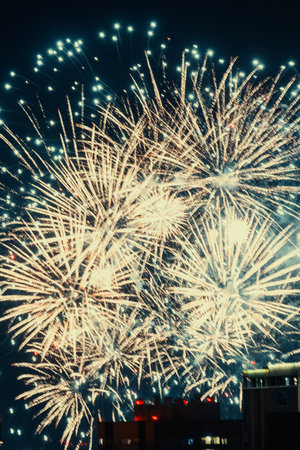 A vibrant display of golden fireworks bursts across the night sky, illuminating the darkness with a...