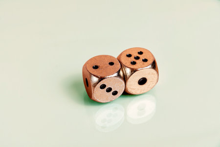 Two golden casino dice with black dots on reflecting green surface. Gambling and betting concept...