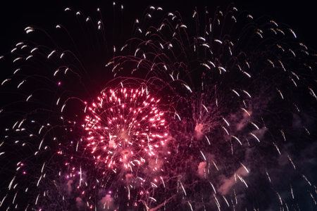 Red vibrant fireworks display illuminates the night sky with bursts of red and white light