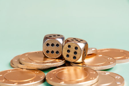 Golden casino dice with 6 dots lay on top of a stack of golden coins. The dice are both showing sixの写真素材