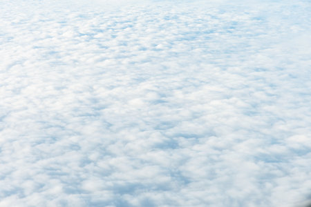 Aerial view of a vast expanse of puffy, white clouds resembling a sea. The soft, ethereal quality of...