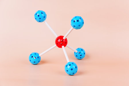A colorful molecular model with red and blue spheres connected by white sticks rests against a soft...