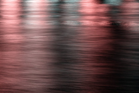 A dreamy abstract image of blurred reflections on water, cast in shades of rose and dark grey
