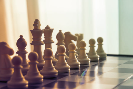 A close-up studio shot captures the elegance of white chess pieces aligned on a chessboard, ready for a strategic battleの写真素材