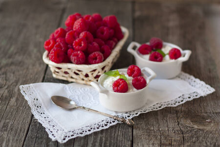 dessert from cottage cheese and raspberries on a white napkin and fresh raspberries in a basket on a...