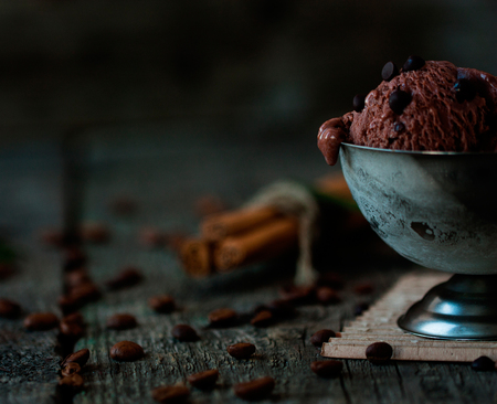 Dark chocolate ice cream with chocolate drops in a metal ice-cream bowl on a dark wooden backgroundの写真素材