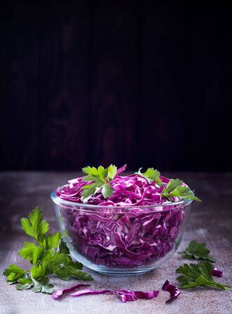 Homemade salad of fresh red cabbage and parsley in a bowl on a dark wooden backgroundの写真素材