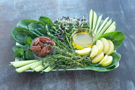Romano lettuce leaves, fresh cucumber and green Apple, sliced, microgreens, fresh thyme, mint, pecans and olive oil on wooden tableの写真素材
