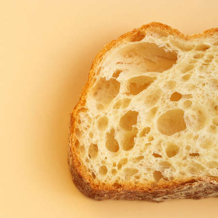 A slice of traditional Italian ciabatta bread with yeast holes close-up. food background