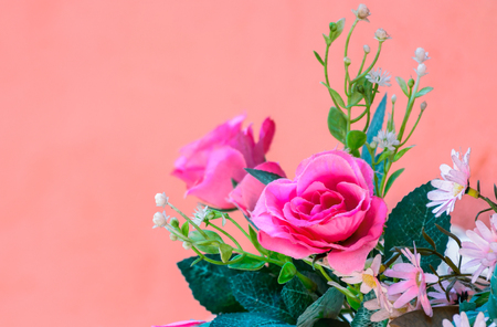 Pink artificial Flowers on orange wall in resort, Thailand.の写真素材